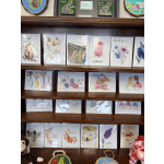 Display shelf of watercolor greeting cards with floral designs and birthday messages