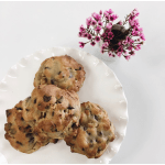 Plate of chocolate chip cookies beside a small white vase with pink blossoms