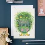 Green owl illustration on a white card with pink flowers