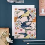 Decorative stationery with bird illustrations and floral accents on a blue surface
