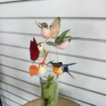 Decorative hummingbird picks in a glass vase with green filler