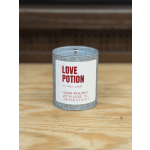 Metal tin candle labeled Love Potion on a wooden surface
