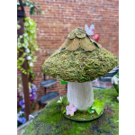 Moss-covered mushroom sculpture with small pink flowers