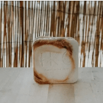 Square candle tin with a brown-and-cream label on a table