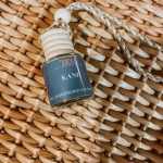 Small hanging glass bottle with a blue label on a woven mat