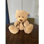 Plush teddy bear with a brown ribbon sitting on a table