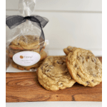 Chocolate chip cookies on a wooden board with a wrapped cookie bag behind them