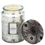 A scented candle in a glass jar with a patterned lid