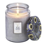 Lit scented candle in a textured glass jar with a patterned lid