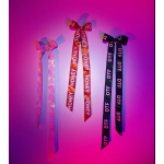 Three decorative ribbon bows hang on a pink wall.