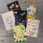 Five assorted greeting cards with colorful illustrated designs
