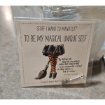 A packaged card with a witch illustration and a small silver wand charm