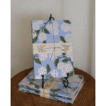 Stack of floral notebooks tied with blue string on a display stand