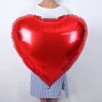 Person holding a large red heart-shaped balloon