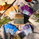 Assorted tea packets and a mug arranged on a cloth.