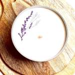 Round white candle with a small purple floral sprig on top