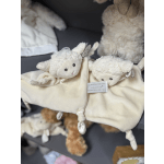 Two cream-colored plush lamb toys with a blanket