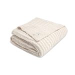 Folded cream-colored plush blanket with a small label