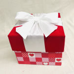 Red gift box with a white ribbon bow and heart-patterned base