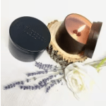 White rose beside two round candles in dark containers