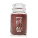 Jar candle with a brown label and autumn-themed artwork