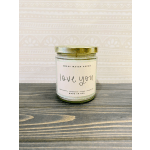 A glass candle jar with a gold lid labeled "love you"