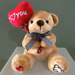 Tan teddy bear holding a red heart plush that says I love you