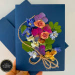 Navy greeting card decorated with colorful dried flowers tied with twine and a matching envelope.
