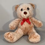 Plush teddy bear with a red bow sitting against a plain background