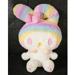 Pastel rainbow plush character with a large bow on a black background