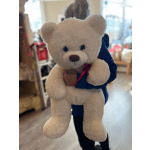 Large white teddy bear with a red ribbon being held up indoors