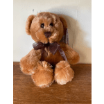 Brown plush teddy bear with a ribbon bow sitting on a wooden surface