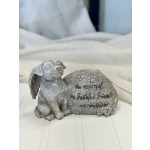 Memorial dog figurine beside a stone plaque with an engraved tribute