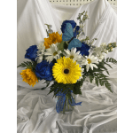 Bouquet of blue roses, white daisies, and yellow gerbera daisies in a glass vase