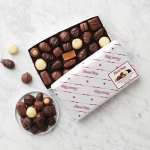 Box of assorted chocolates with a few pieces scattered beside it