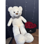 White teddy bear beside a box of red roses