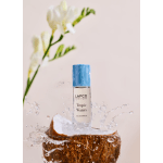 Perfume bottle on a coconut half with water splashing around it