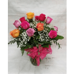 Bouquet of multicolored roses in a glass vase with pink ribbon