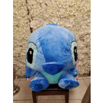 Large blue plush character in front of a white flower wall
