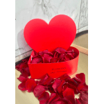 Red heart-shaped gift box filled with rose petals