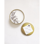 Two gold tin candles on a white surface, one open with dried lavender inside