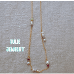 Gold necklace with pearl and bead accents on beige fabric