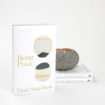 Book with a lit stone candle beside two stacked books