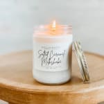 Lit candle in a glass jar with a metal lid beside it