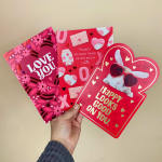 Hand holding three red and pink Valentine’s Day cards