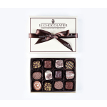 Box of assorted gourmet chocolates with lid and ribbon beside it