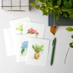 Floral watercolor greeting cards with envelopes and a green pen on a white surface