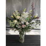 Tall floral arrangement in a glass vase with white orchids and roses