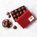 Box of chocolate truffles with a few pieces on a plate
