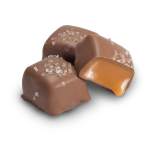 Three chocolate-covered caramels with sea salt on a white background